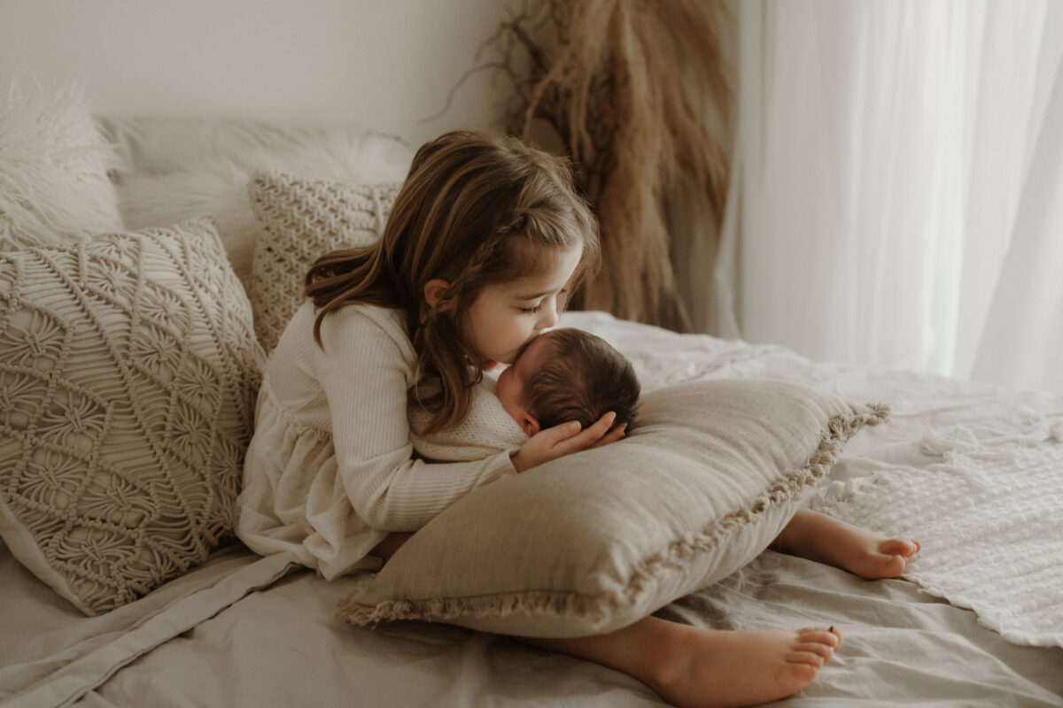 detailed image of sibling kissing baby during newborn photography session with Jen Jacobowitz in Richmond VA